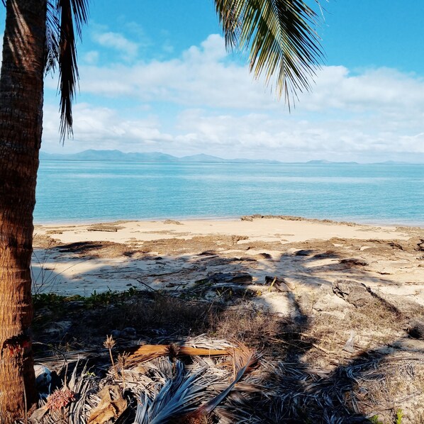 Una platja amb vista clara a l'oceà i muntanyes allunyades.