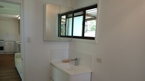 Una cocina moderna con armarios blancos, horno integrado y ventana sobre el fregadero.