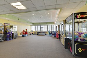 Een ruime indoor speelhal met diverse spelautomaten en een groot raam dat natuurlijk licht binnenlaat.