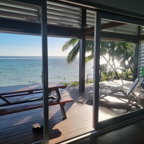 A beachside patio with a wooden deck, a picnic table, and lounge chairs. - Premier and Stunning Beach Front Location UNIT 4 (Nikao)