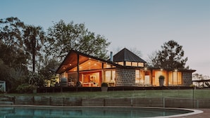 A modern house with a large glass facade, a stone exterior, and a swimming pool in the foreground. - Luxurious Unique, Private Paradise-Kangaroo Manor (Yarra Valley)