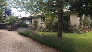 A residential house with a gravel driveway, a well-maintained lawn, and various shrubs and small trees. -  Located near Eely Point  (Wanaka)