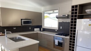 A modern kitchen with a built-in microwave, stove, oven, and refrigerator. -  Located near Eely Point  (Wanaka)