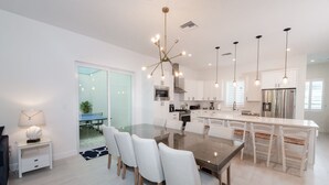 Une cuisine moderne avec des armoires blanches, un grand îlot central et des luminaires suspendus.