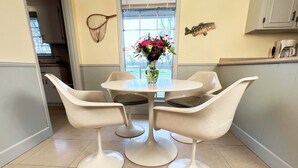 A modern kitchen with a round table and four white chairs. There is a vase with flowers on the table, and a fish decoration on the wall. - Guest House at Historic Ten Horse Farm near Bainbridge and Lake Seminole (Bainbridge)