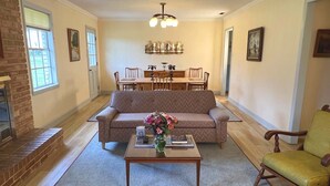 A living room with a sofa, a coffee table with a vase, a wooden chair, and a fireplace. - Guest House at Historic Ten Horse Farm near Bainbridge and Lake Seminole (Bainbridge)