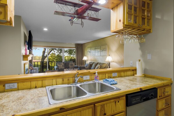 A kitchen with wooden cabinets, a double sink, and a dishwasher.