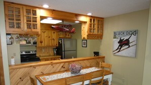 A kitchen with wooden cabinets, a refrigerator, a stove, and a dining table with chairs. - No Worries at Summit Village! (bellaire)