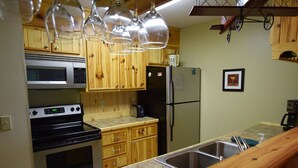 A kitchen with wooden cabinets, a stainless steel sink, a microwave, a stove, and a refrigerator. - No Worries at Summit Village! (bellaire)