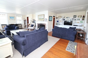 A living room with two dark sofas, a white coffee table, a fireplace, and a television on a white stand. - Private & Spacious 5 Bedroom Home (1607) (Wellfleet)