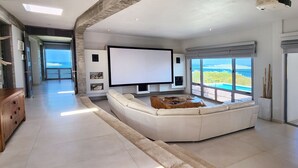 Ein modernes Wohnzimmer mit einem großen Flachbildfernseher, einem weißen Ecksofa und einem Holztisch.
