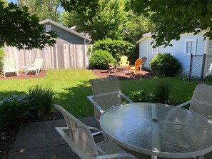 Relax in the serene backyard patio surrounded by lush greenery and comfortable seating.