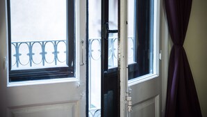 Eine teilweise geöffnete Tür, durch die man einen Balkon mit einem Metallgeländer sieht.