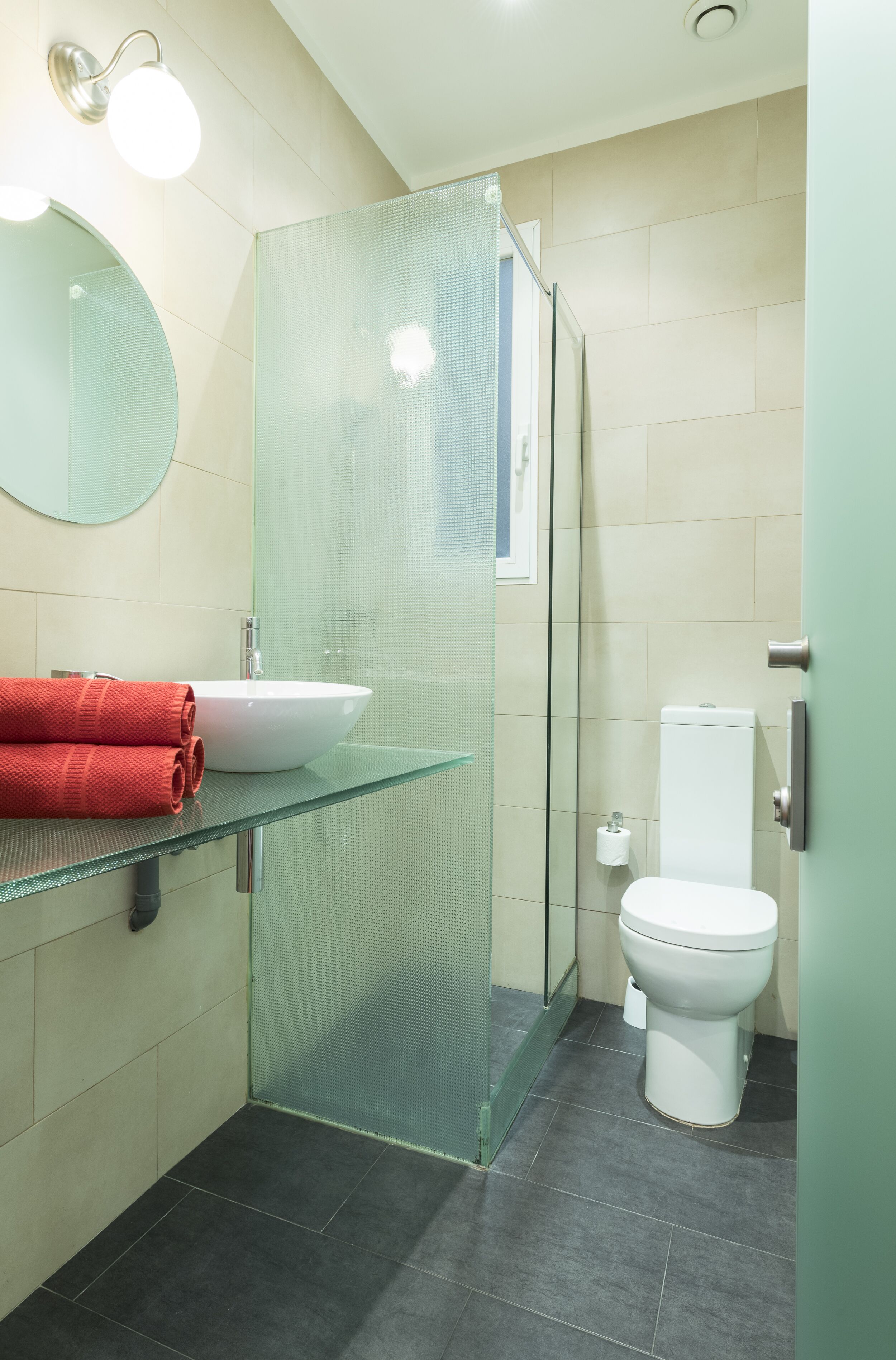 A modern bathroom with a glass shower enclosure, a white sink, and a toilet.