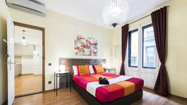 Ein Hotelzimmer mit Bett, einem Gemälde, einer Chandelüster und Blick ins Freie.