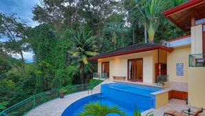 Ein Haus mit Swimmingpool, umgeben von üppiger Vegetation.