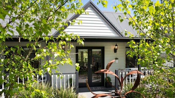 A house with a white exterior, a dark front door, and a small porch with a potted plant. - Cottage 4A- sweet retreat with spa in Daylesford (Daylesford)