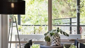 A dining area with a table set for two, a potted plant, a polka-dotted mug, and a lamp. - Cottage 4A- sweet retreat with spa in Daylesford (Daylesford)