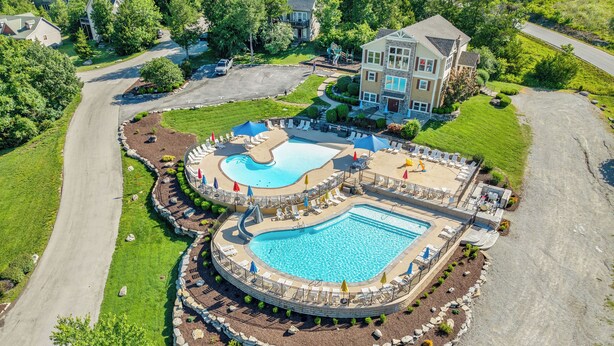 Een groot resort met meerdere zwembaden, inclusief een centraal gelegen zwembad, omringd door terrasjes en een aangelegde tuin.