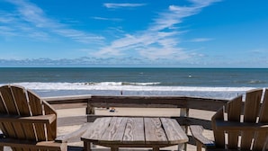 A wooden deck with chairs and a table overlooking the ocean. - 600 Nags Head Ocean-Front Completely Renovated (Nags Head)