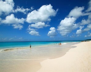 Een strand met heldere lucht en enkele mensen.
