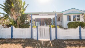 A white picket fence, a covered porch, and a sign reading "PICNIC COTTAGE." - Picnic Cottage, Lovely home near the beach (PICNIC BAY)
