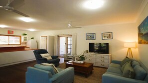 A living room with a television, two sofas, a coffee table, and a dining area with a counter and chairs.