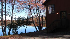 Una cabaña junto a un lago, con fachada de madera y un pequeño porche.