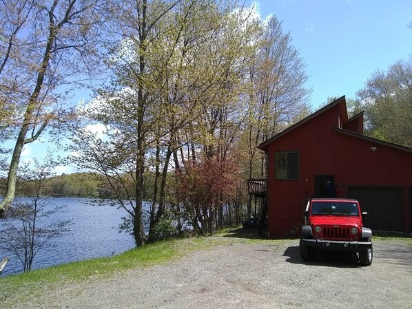 A red building with a gravel driveway and a parked red vehicle.