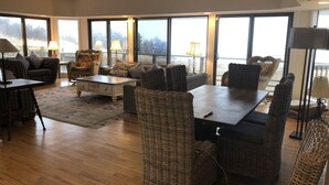 Ein geräumiges Wohnzimmer mit großem Fenster, Korbmöbeln und Holzboden.