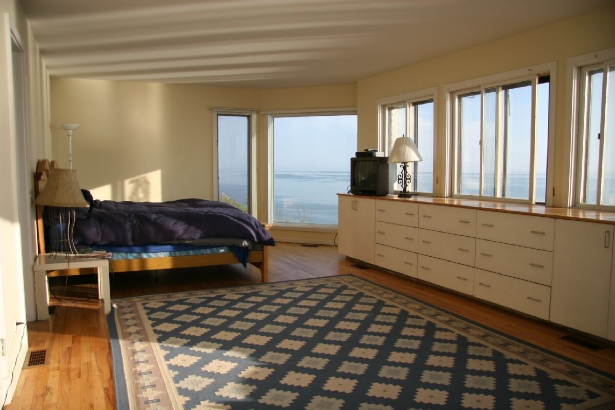 Un dormitorio con cama, escritorio, lámpara, televisor y vista al mar.