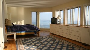 Ein Schlafzimmer mit Bett, Schreibtisch, Lampe, Fernseher und Meerblick.