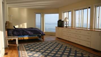 Un dormitorio con cama, escritorio, lámpara, televisor y vista al mar.