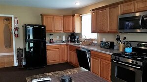 A kitchen with wooden cabinets, a black refrigerator, a microwave, a stove, and a toaster. - Visiting Cooperstown NY or Oneonta NY areas stay at Abel's Acre's Hideaway House (Mt Vision)