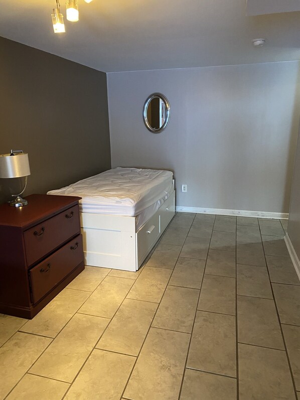 A bedroom with a bed, dresser, and a round mirror on the wall.