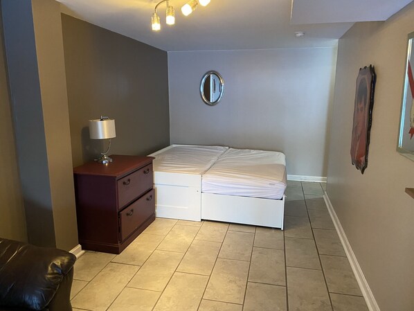 Un dormitorio con cama, cómoda, espejo y lámpara en el techo.