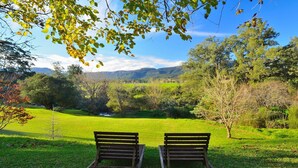 A park with two wooden benches facing a grassy field and a mountain backdrop. - ONLY PROPERTY IN THE VILLAGE WITH A POOL AND PRIVATE RIVER FRONTAGE (Kangaroo Valley)