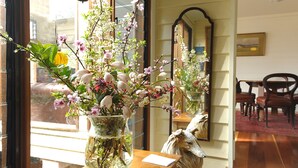 A room with a large window, a vase with flowers, a mirror, and a wooden table with chairs. - ONLY PROPERTY IN THE VILLAGE WITH A POOL AND PRIVATE RIVER FRONTAGE (Kangaroo Valley)