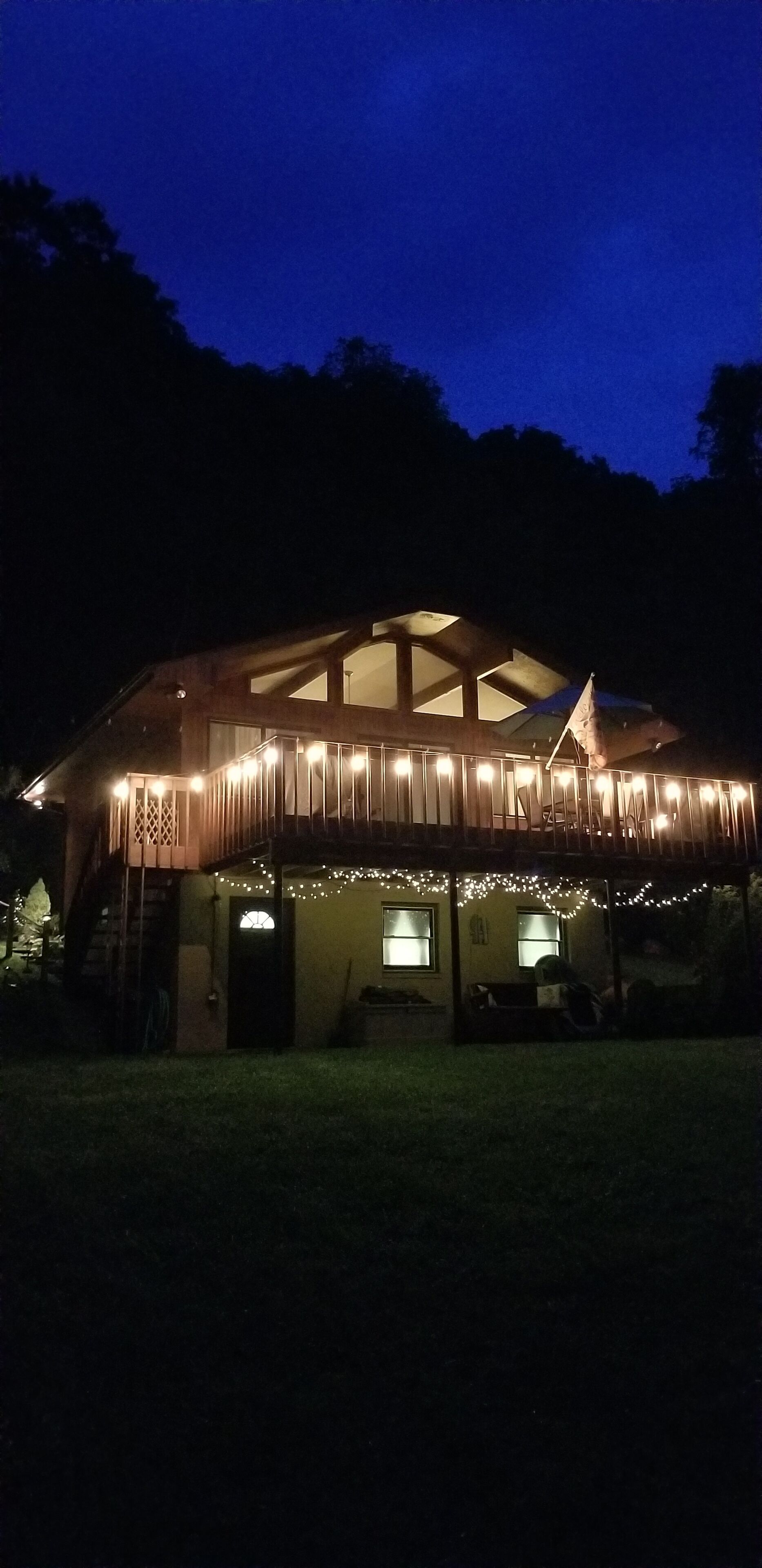 Une cabane en bois dotée d’une grande véranda, de nombreuses fenêtres et de guirlandes lumineuses.
