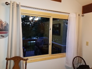 Een kamer met een grote schuifglazen deur die uitkomt op een terras, een houten stoel en een kleine tafel.