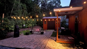Een houten hut met een veranda, lichtjes en een bank.