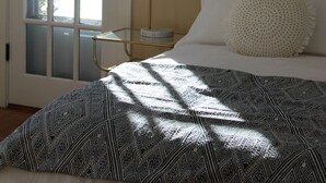 A bedroom with a bed, a bedside table, a lamp, a framed picture on the wall, and a door with frosted glass panels.
