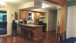 A spacious kitchen with wooden cabinets, a central island with stools, a built-in oven, and a microwave.