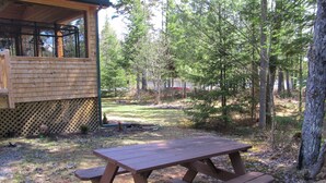 A picnic table in a wooded area with a wooden cabin in the background.