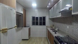 Een moderne keuken met witte kasten, een raam en een betegelde spatwand.
