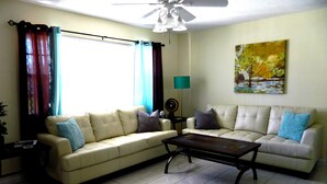 A living room with two sofas, a coffee table, a floor lamp, and a painting on the wall. - 5 Min Walk to Beach, Heated pool w/ spa jets, Large private lanai facing SW. (Marco Island)
