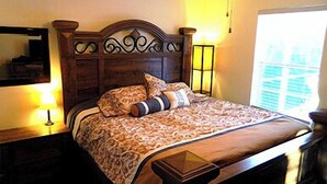 A neatly made bed with patterned bedding, a wooden headboard, and bedside lamps. - 5 Min Walk to Beach, Heated pool w/ spa jets, Large private lanai facing SW. (Marco Island)