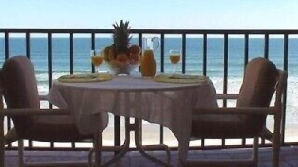 A table with chairs set on a balcony overlooking the ocean. - Oceanfront - Beautiful, Direct Oceanfront. Extra Large 1 Bedroom, 1+ Bath (New Smyrna Beach)