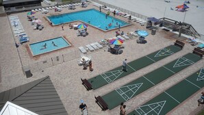 A rooftop pool area with multiple pools, sun loungers, and shuffleboard courts. - Oceanfront - Beautiful, Direct Oceanfront. Extra Large 1 Bedroom, 1+ Bath (New Smyrna Beach)