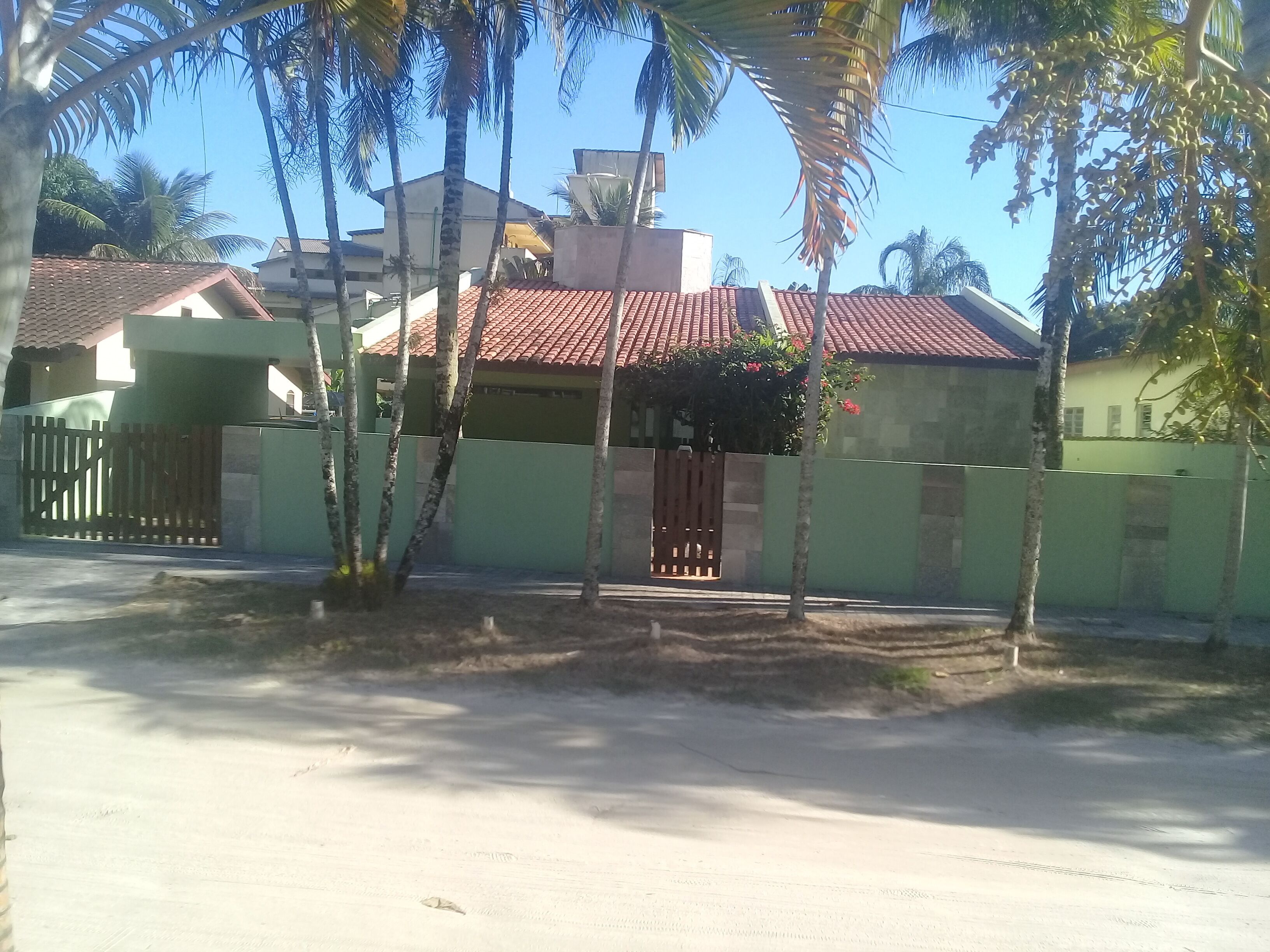 A residential area with a house featuring a red-tiled roof, a gated entrance, and a small porch.